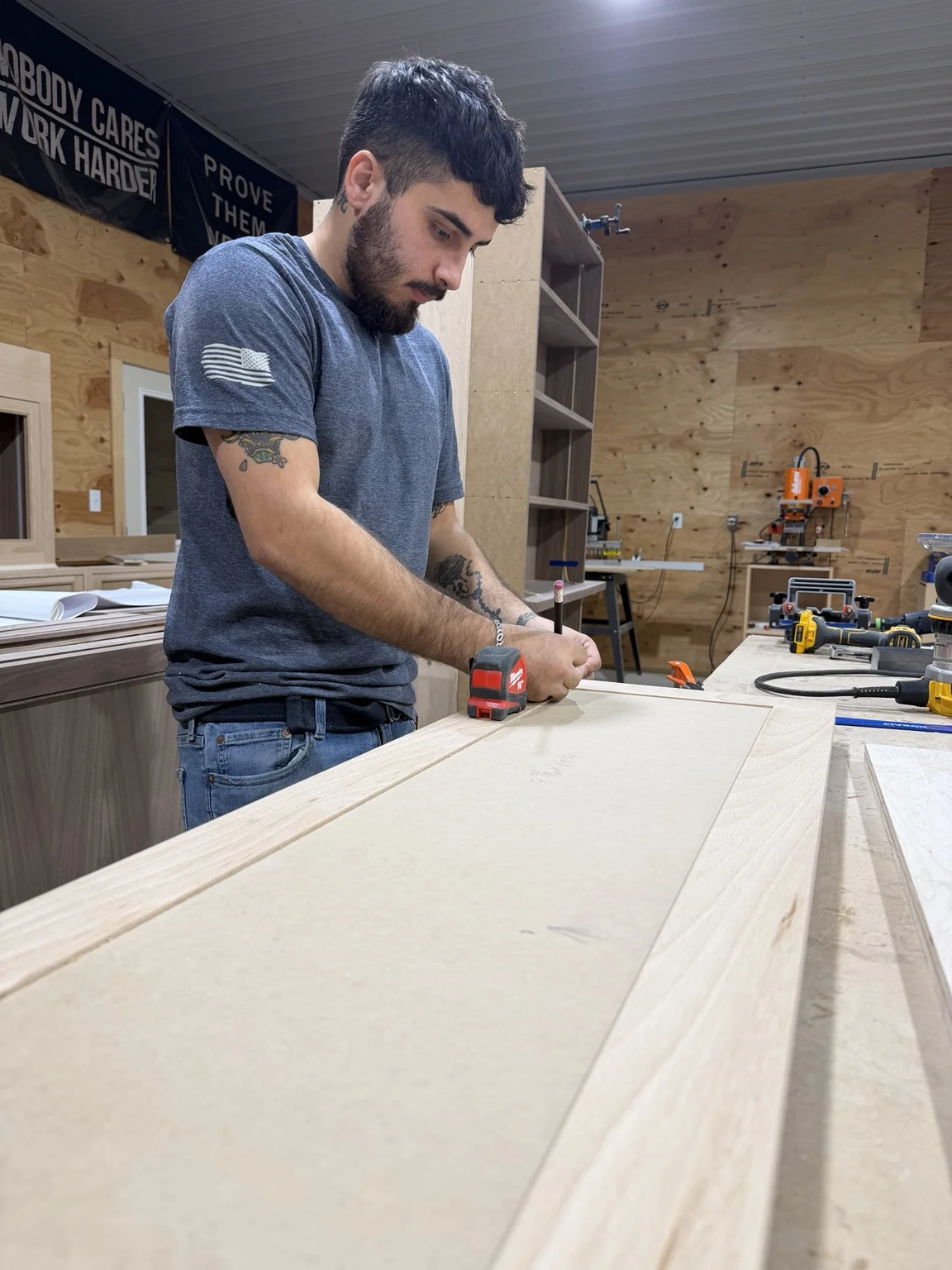 Craftsperson marking a large unfinished cabinet component at the workbench