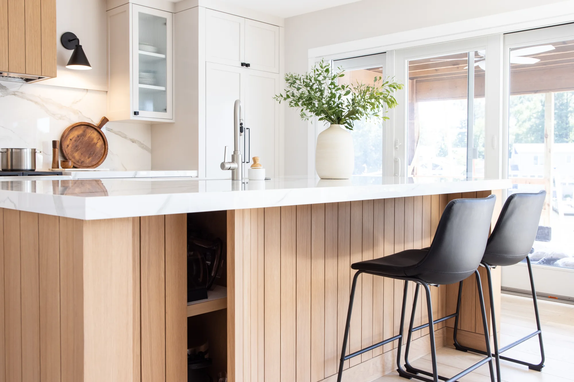 Fluted wood island with pale countertop and dark stools
