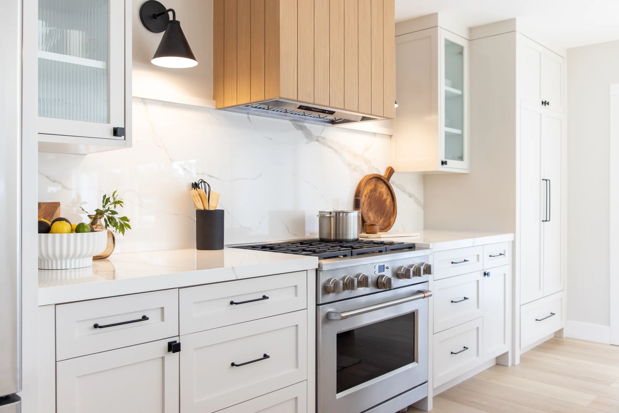 White cabinetry with a wood range hood and pale backsplash