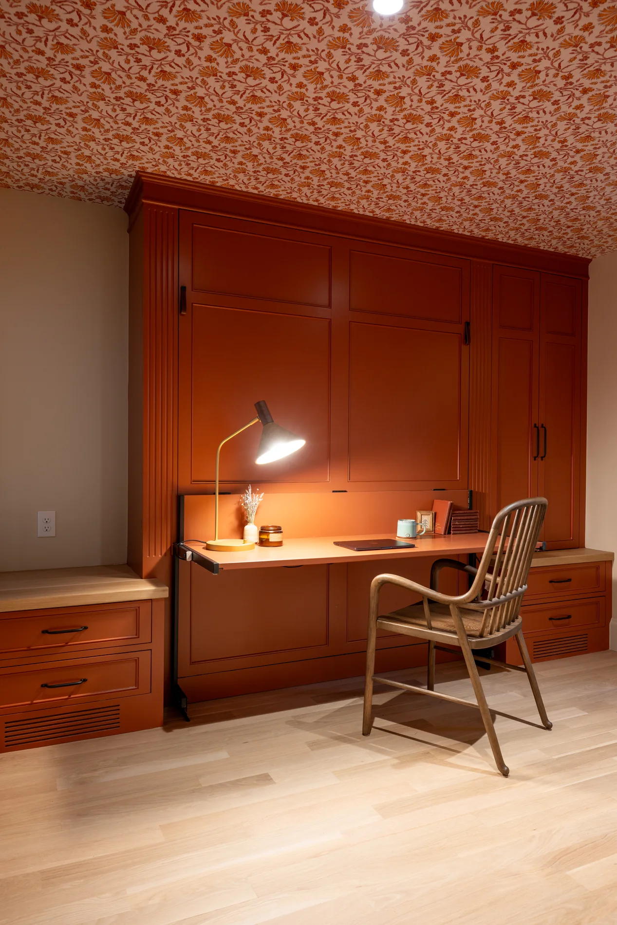Wood built-in desk beneath a patterned terracotta-colored wall